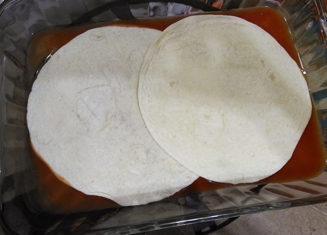 Place two tortillas along the bottom of your dish. They will overlap. If you make a bigger recipe or use a bigger dish than this for some reason, you might need to tear an extra tortilla in half to make sure the bottom is fairly well covered. 